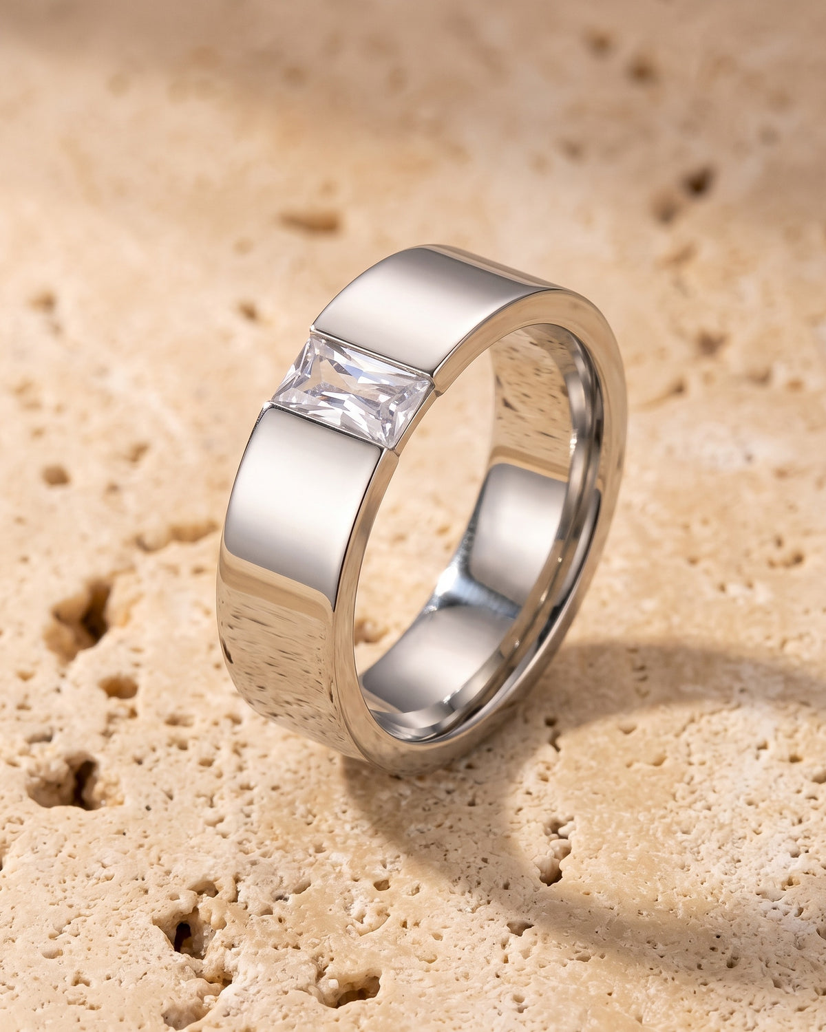 The whole silver-tone Atlas Baguette Cubic Zirconia Ring lying on warm travertine stone