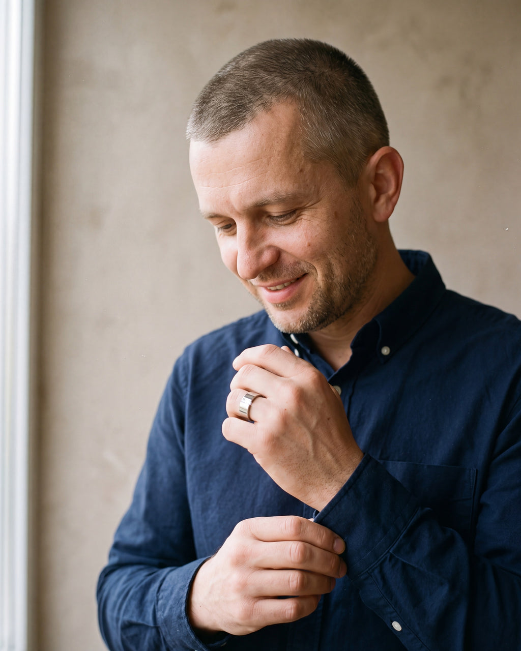 Man in a dark navy cotton oxford shirt by a window wearing the silver-tone Atlas Baguette Cubic Zirconia Ring