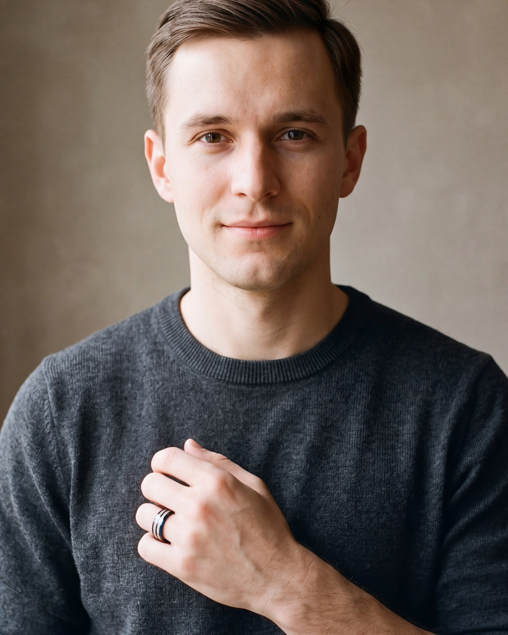 Man in a charcoal sweater with his hand on his chest, wearing the Atlas black and blue tungsten ring