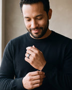 Man in a black sweater adjusting his sleeve, wearing the Atlas black and blue tungsten ring