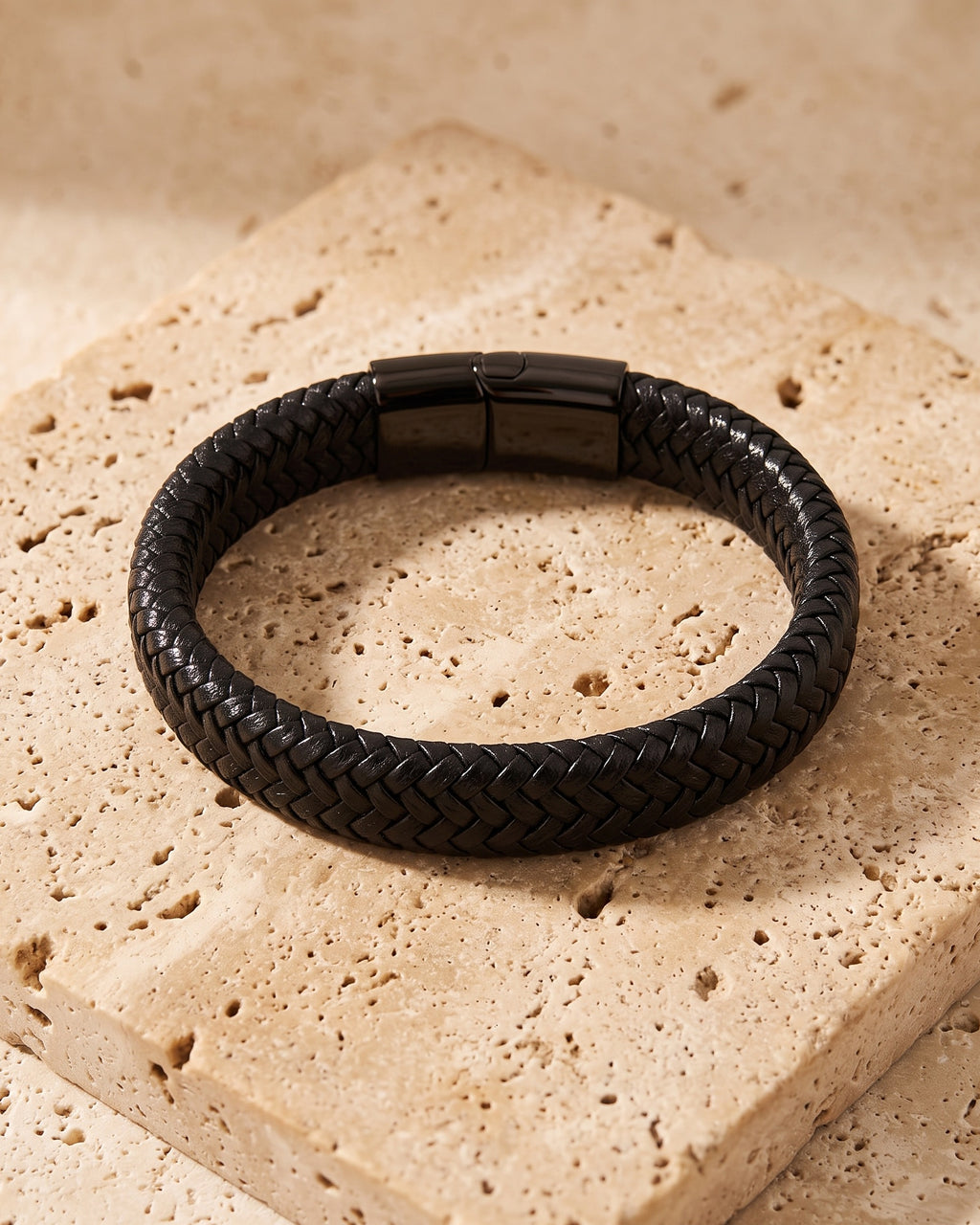 The whole black Atlas black braided leather magnetic bracelet laid on warm stone