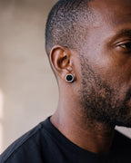 Close-up of the silver Atlas Black Disc Stud Earrings worn at true size