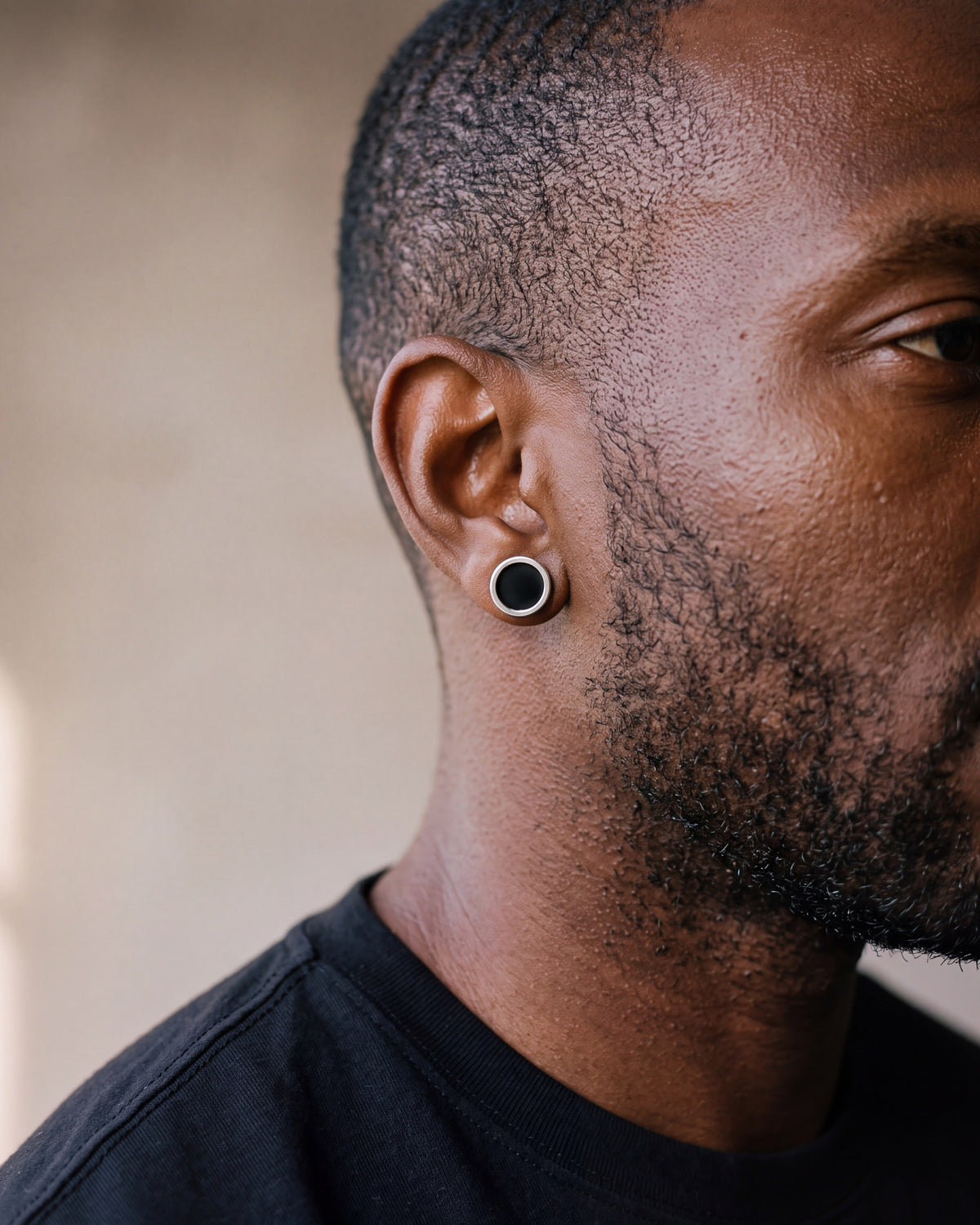 Close-up of the silver Atlas Black Disc Stud Earrings worn at true size
