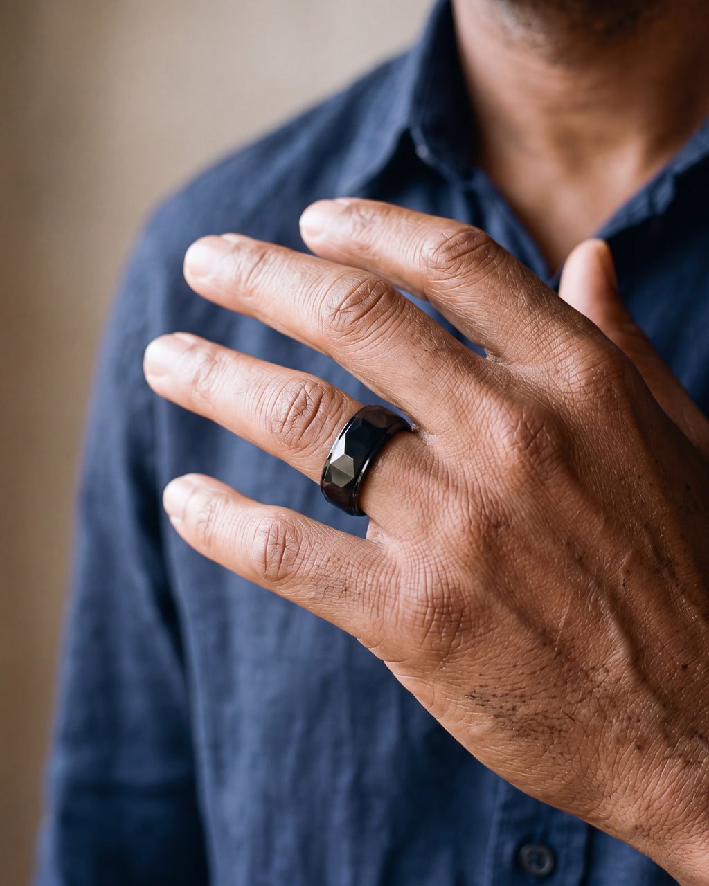 Close-up of the black Atlas black faceted tungsten carbide ring worn by a man, shown at true size