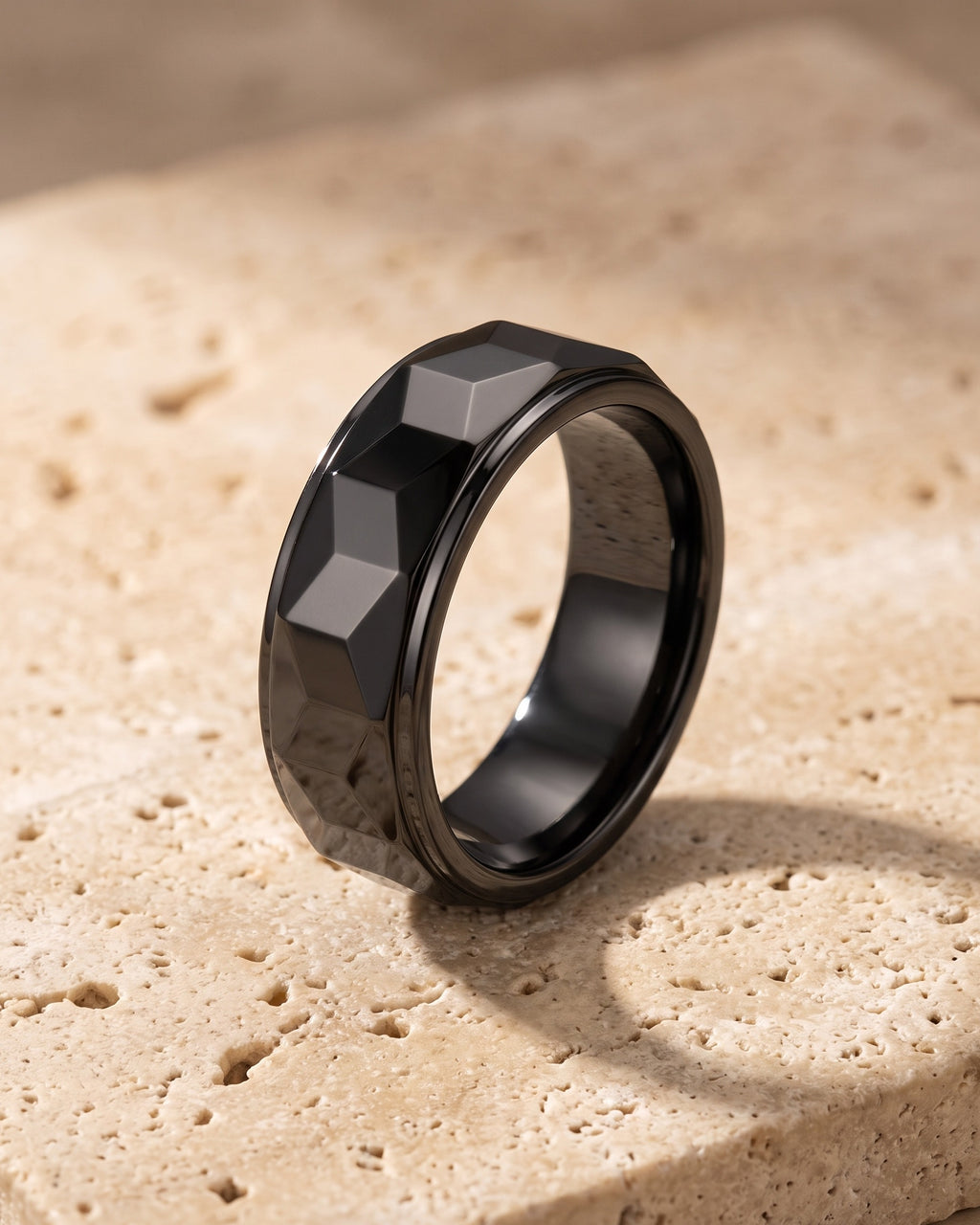 The whole black Atlas black faceted tungsten carbide ring laid on warm stone