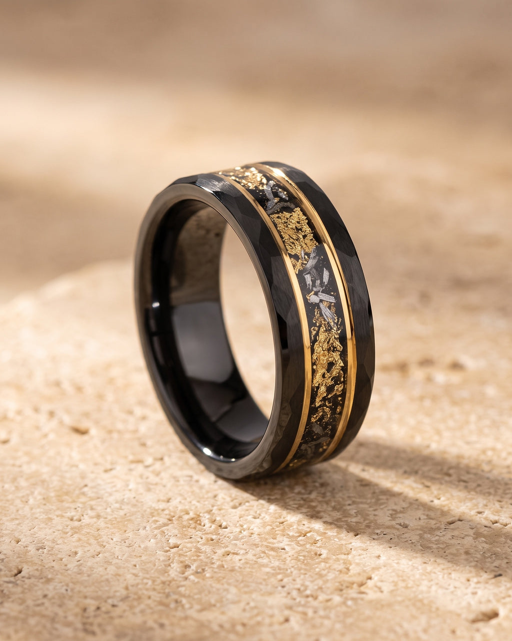 The whole black Atlas black gold-tone flake ring lying on warm travertine stone