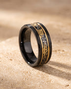 The whole black Atlas black gold-tone flake ring lying on warm travertine stone