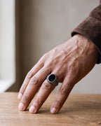Close-up of a man's hand wearing the Atlas black stone signet ring at true size