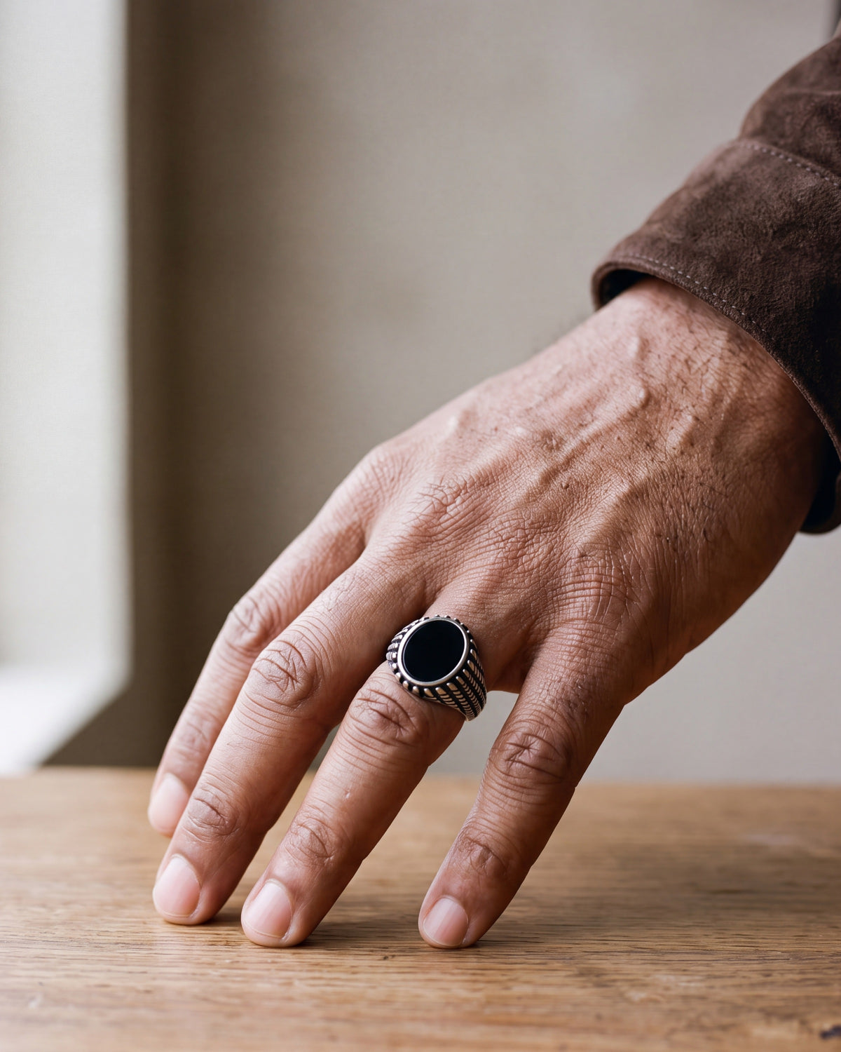 Close-up of a man's hand wearing the Atlas black stone signet ring at true size