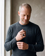 Man in a charcoal sweater adjusting his cuff, wearing the Atlas black stone signet ring