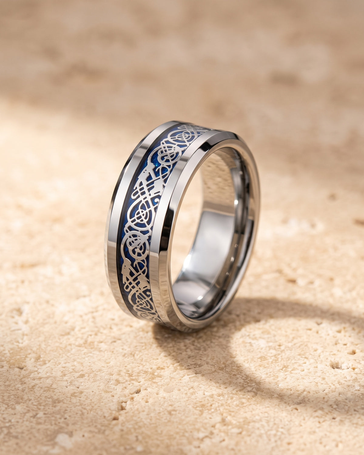 The Atlas blue Celtic knot tungsten ring standing on warm stone