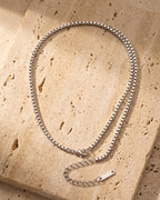 The whole silver Atlas box chain with extender lying on warm travertine stone