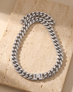 Silver Atlas Miami Cuban chain laid whole on warm stone, fold-over box clasp closed