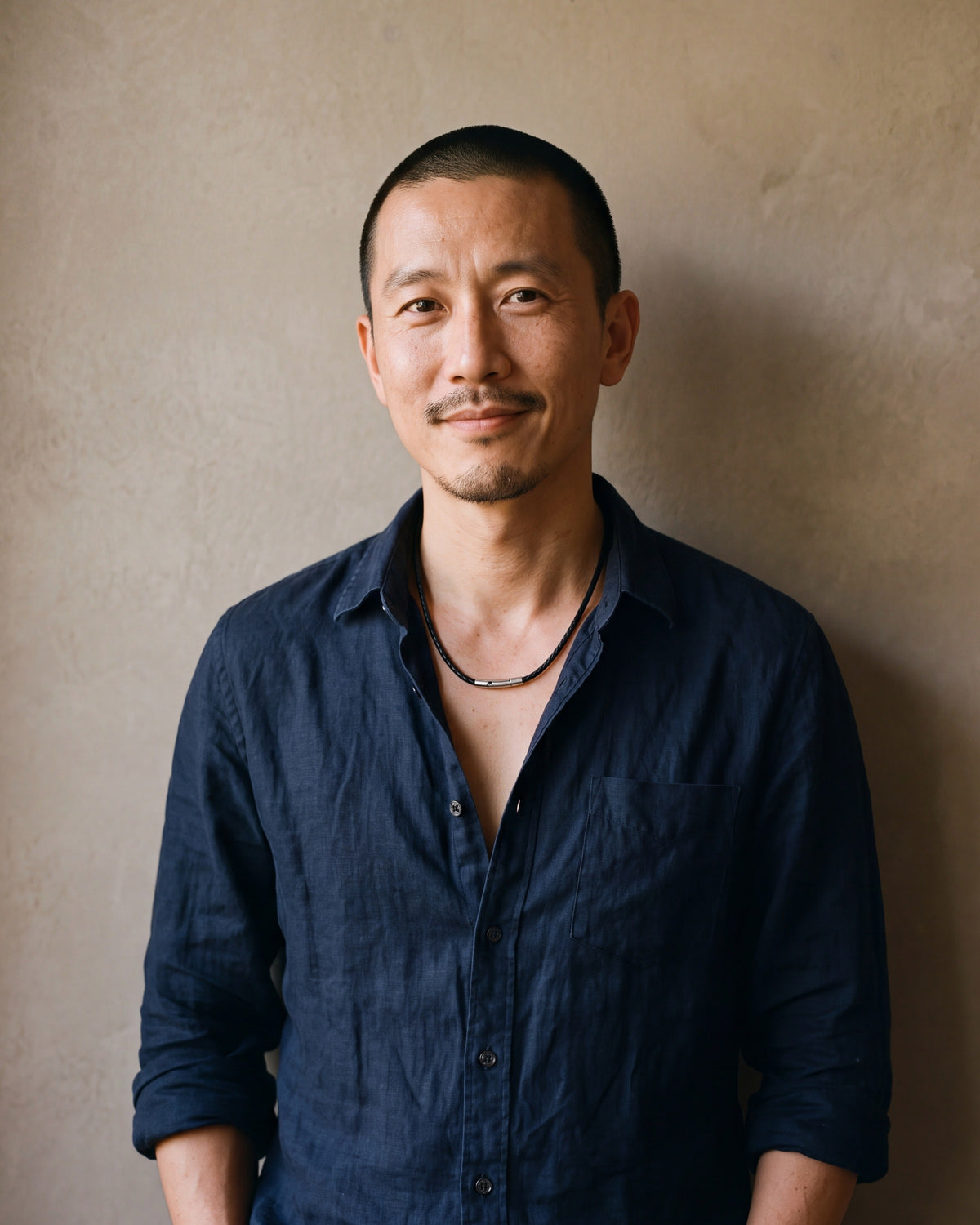 Man in a navy linen shirt wearing the Atlas black braided cord necklace