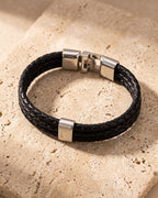 The Atlas braided leather magnetic bracelet closed on warm stone