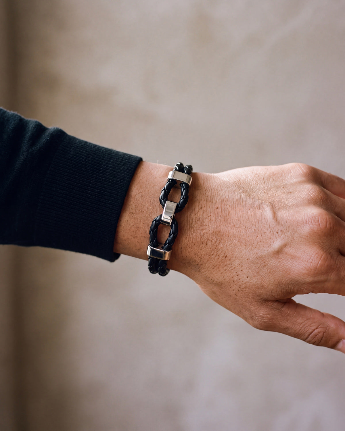 Close-up of the black and silver-tone Atlas braided leather shackle bracelet worn by a man, shown at true size