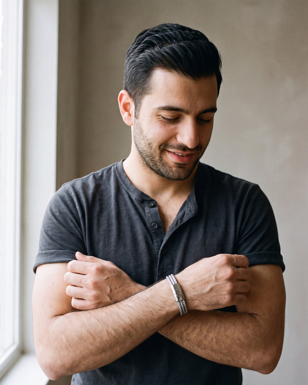 Man in a charcoal cotton henley t-shirt by a window wearing the silver-tone Atlas Braided Magnetic Bracelet