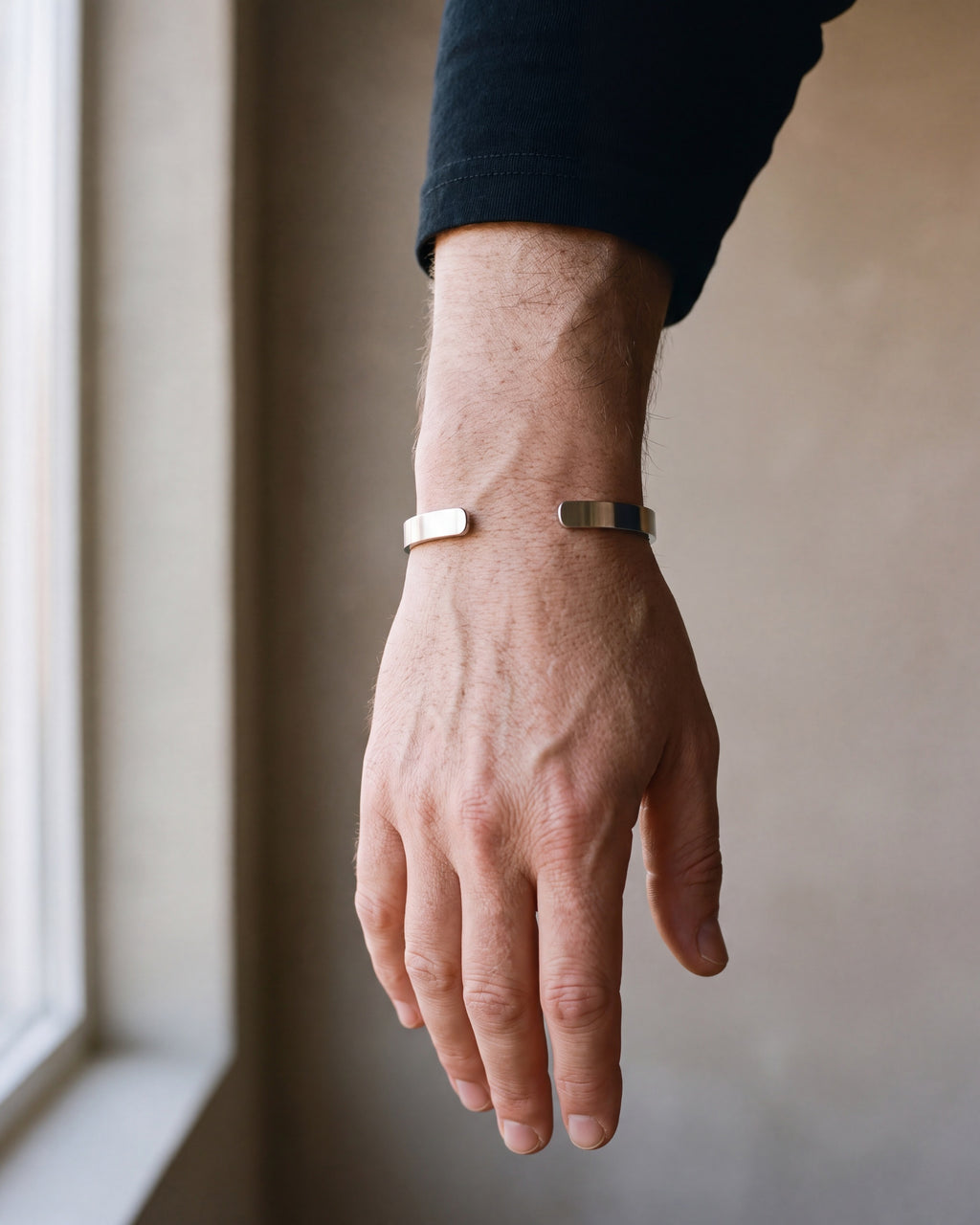 Close-up of the silver-tone Atlas brushed cuff bracelet worn by a man, shown at true size
