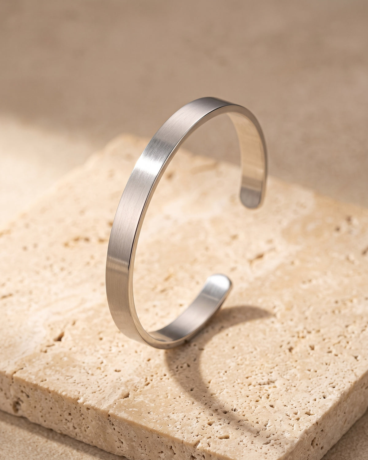 The whole silver-tone Atlas brushed cuff bracelet laid on warm stone