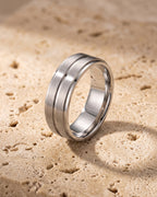 The silver-tone Atlas brushed double groove ring standing on warm stone