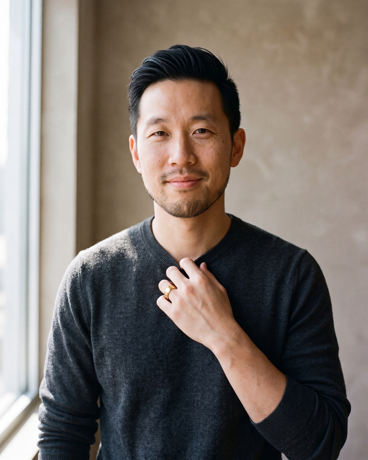 Man in a charcoal sweater by a window wearing the gold-tone Atlas brushed panel ring