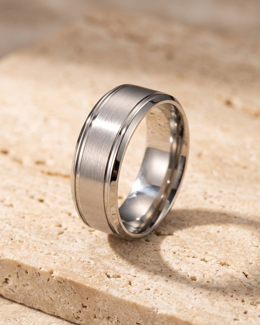 The whole silver-tone Atlas brushed panel ring laid on warm stone
