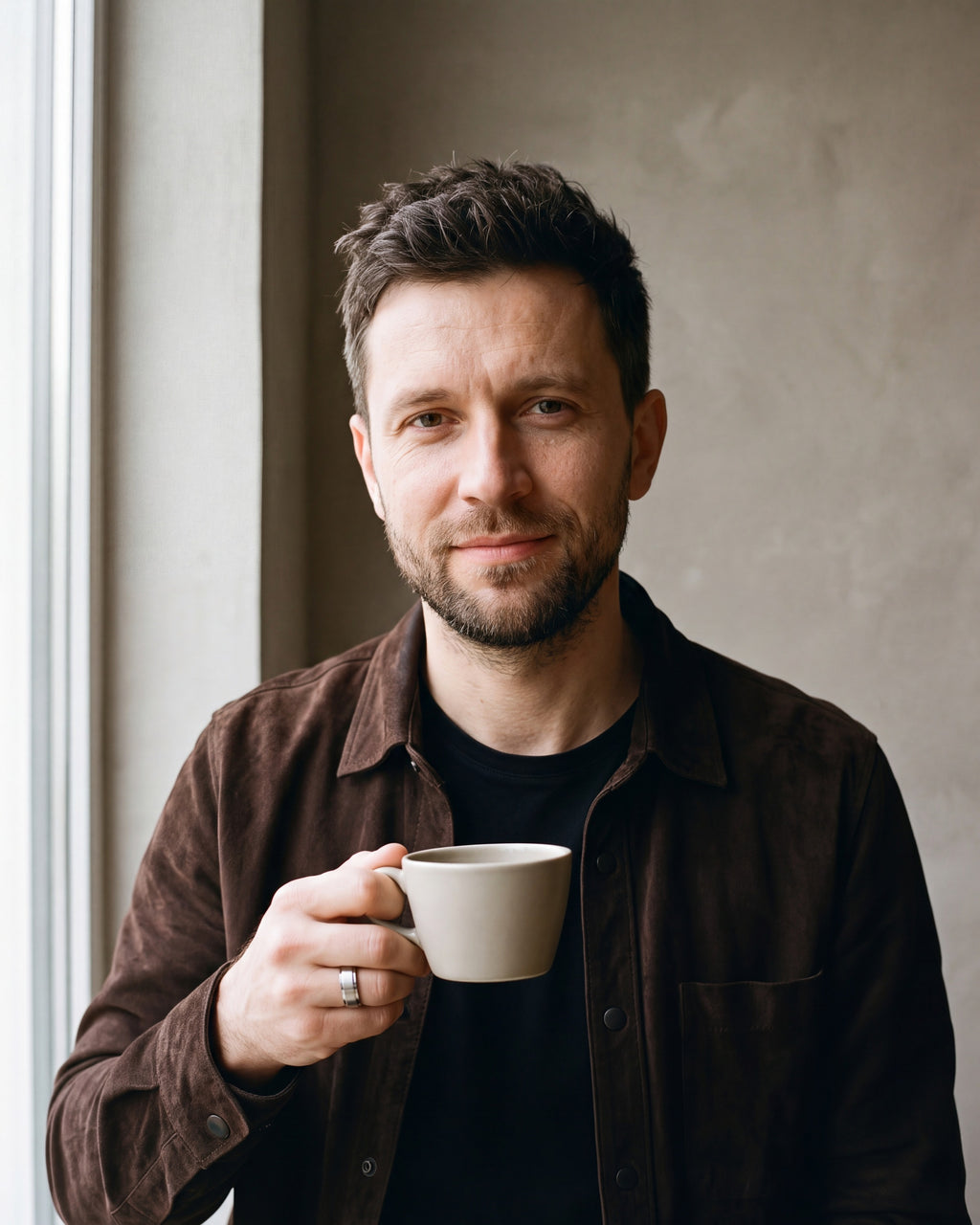 Man in a brown suede overshirt holding a coffee cup wearing the silver-tone Atlas brushed panel ring
