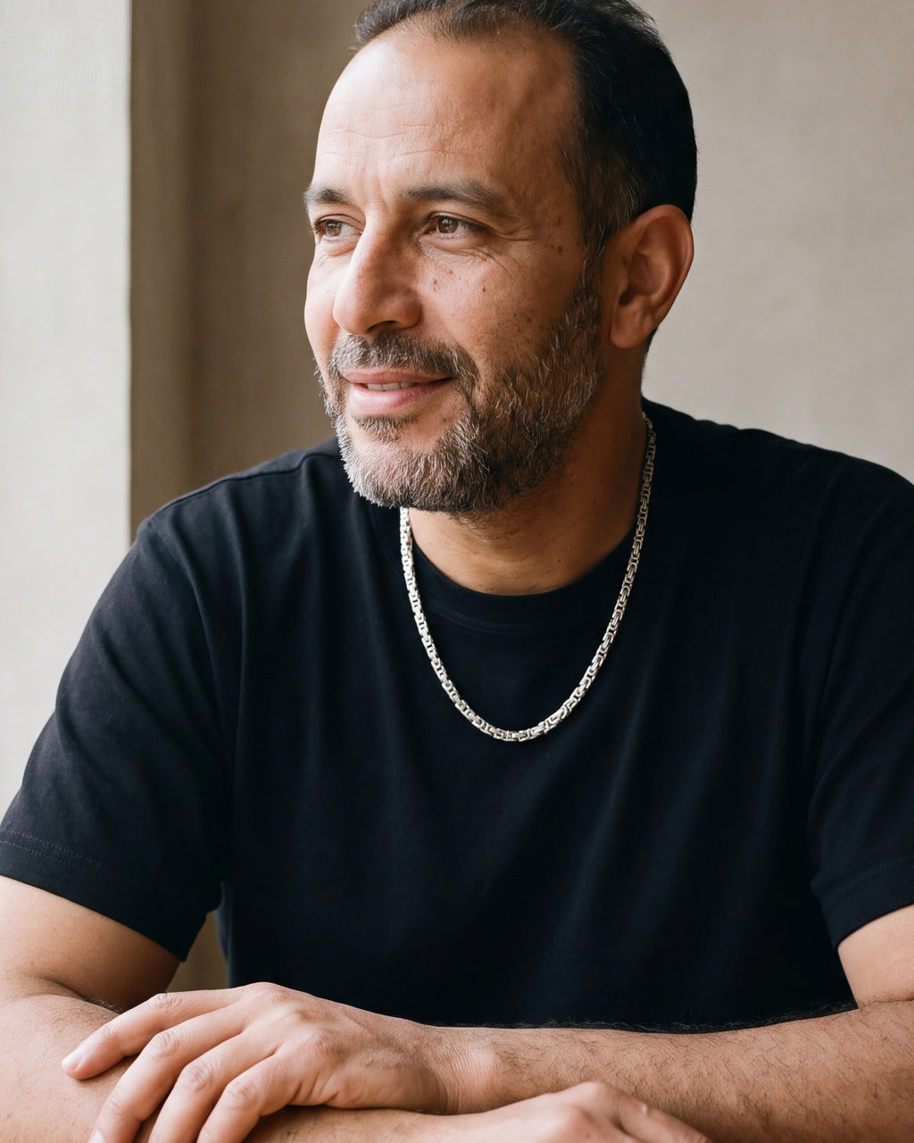 Man in a black t-shirt seated at a table, wearing the 4 mm silver Atlas Byzantine chain
