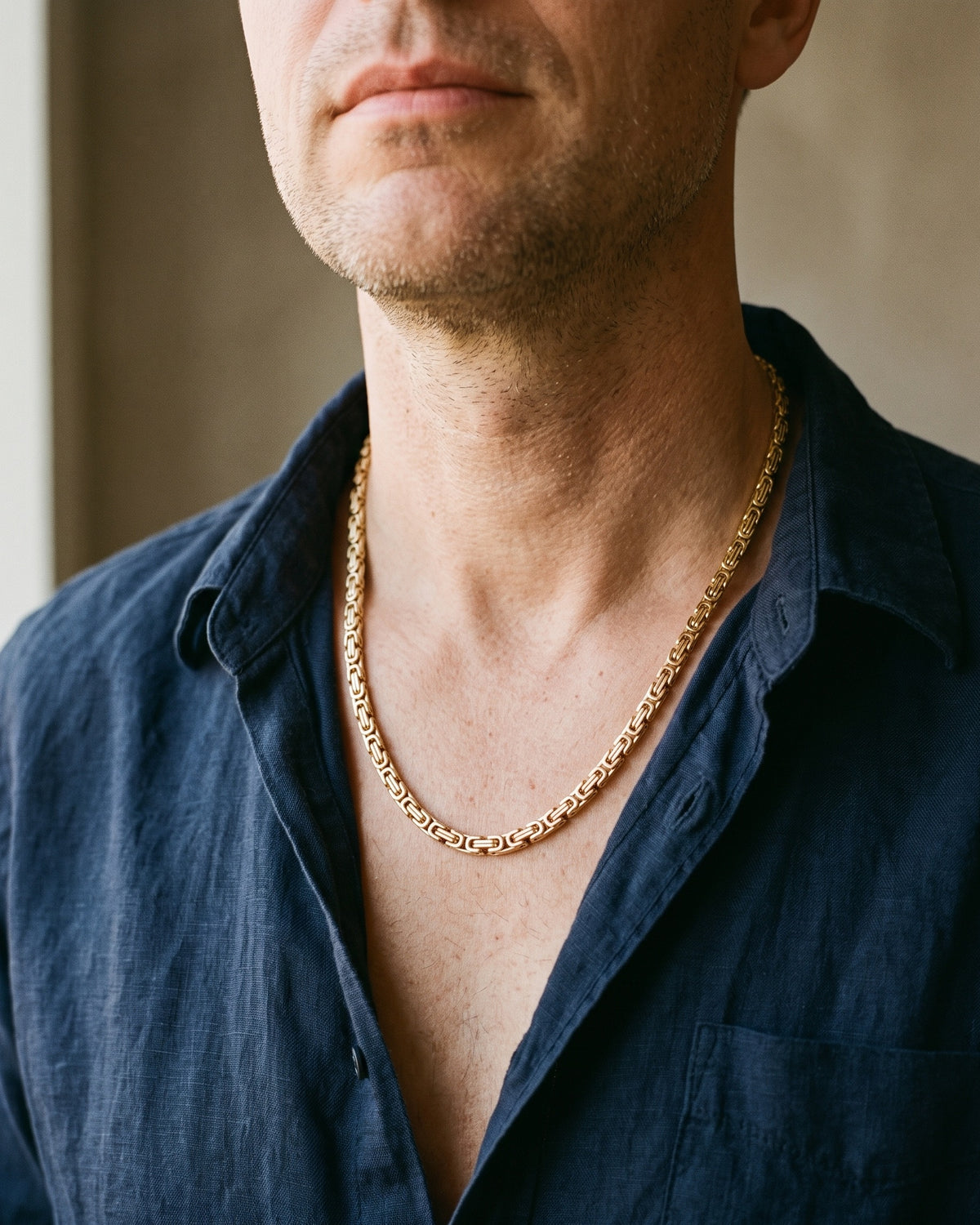 Atlas 4 mm Byzantine chain in gold-tone stainless steel worn on the chest, close-up