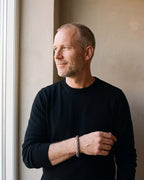 Man in a black sweater by a window wearing the silver Atlas Byzantine link bracelet