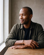 Man in a dark olive overshirt open over a black t-shirt wearing the gold-tone Atlas C-Shaped Cuff Bracelet
