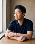 Man in a navy fine-gauge knit polo with an open collar by a window wearing the silver Atlas cable bar bracelet