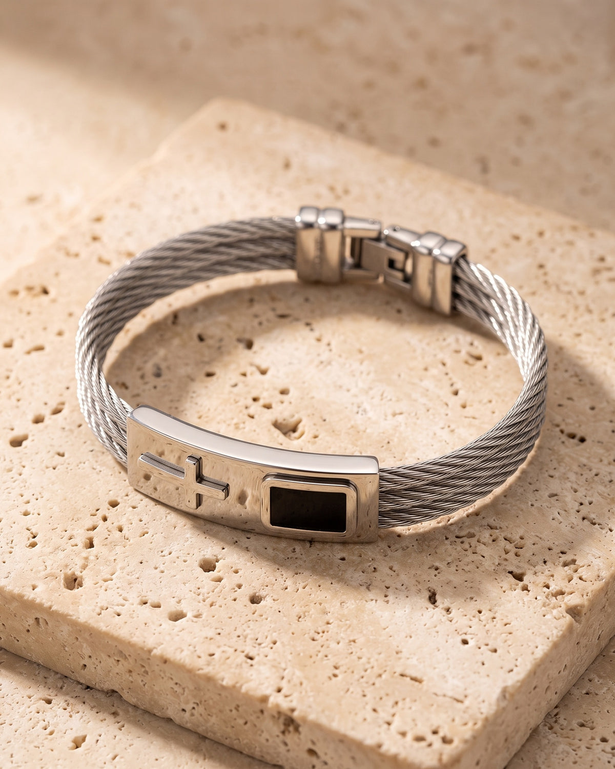 Silver Atlas cable cross bracelet closed on warm stone