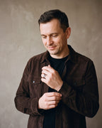 Man in a dark brown suede overshirt open over a black t-shirt wearing the silver-tone Atlas Carbon Fiber Inlay Ring
