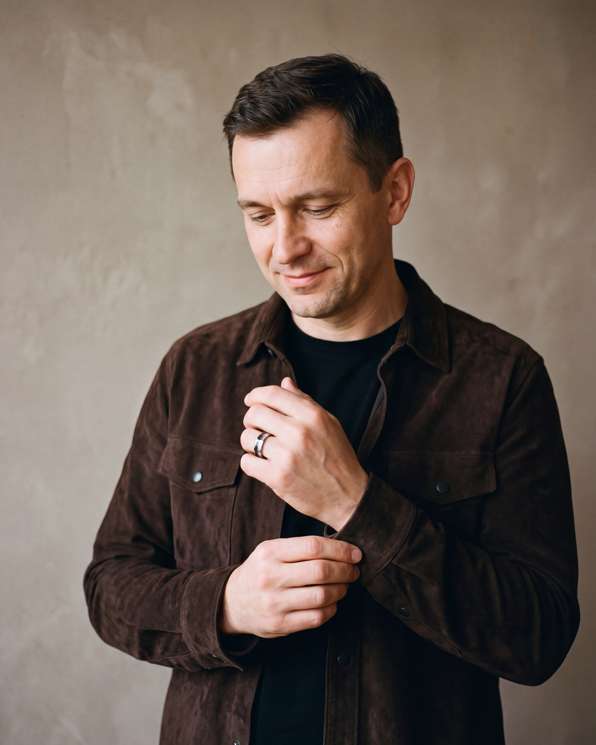 Man in a dark brown suede overshirt open over a black t-shirt wearing the silver-tone Atlas Carbon Fiber Inlay Ring