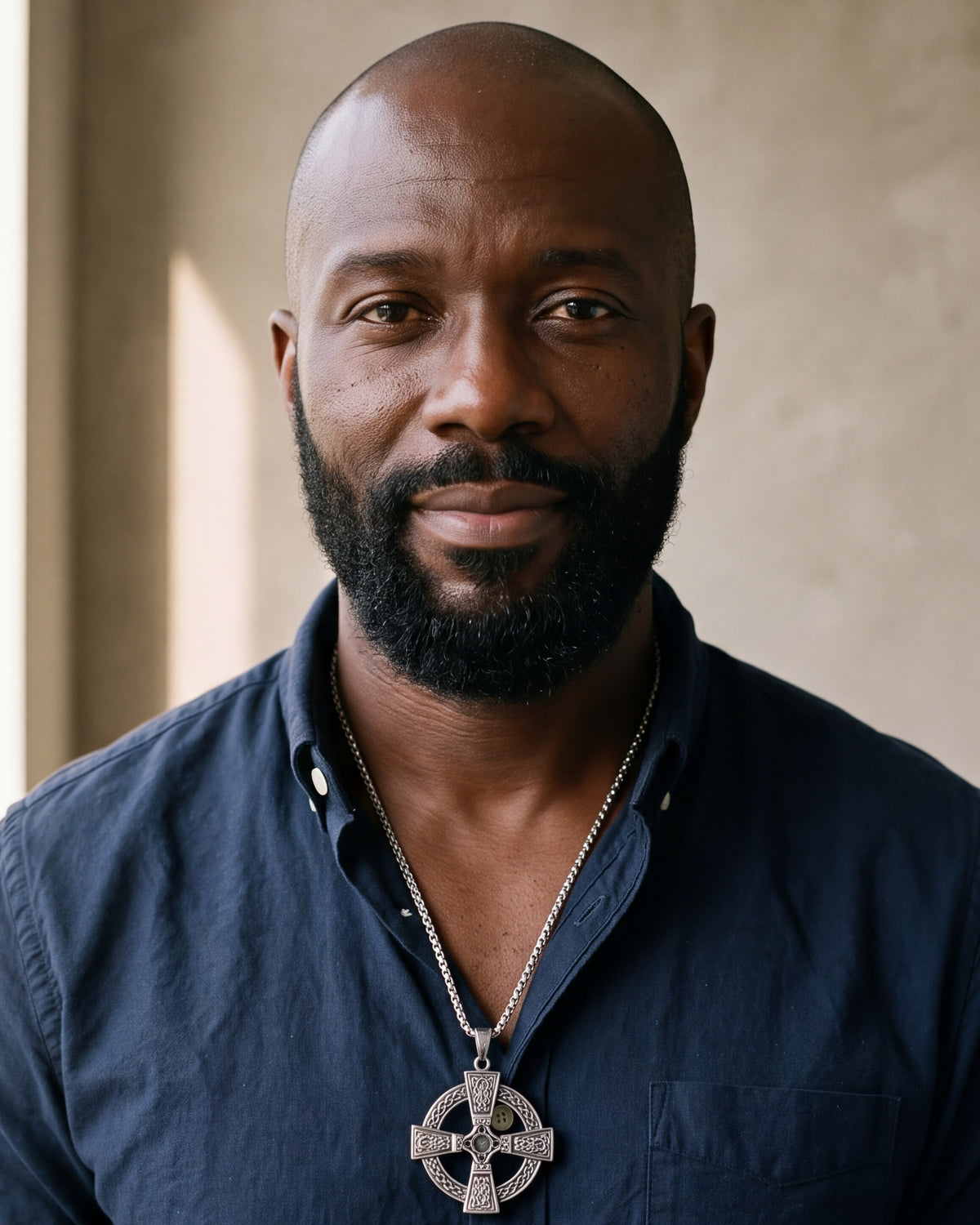 Man in a navy shirt looking at the camera, wearing the Atlas Celtic knotwork cross pendant on a steel box chain
