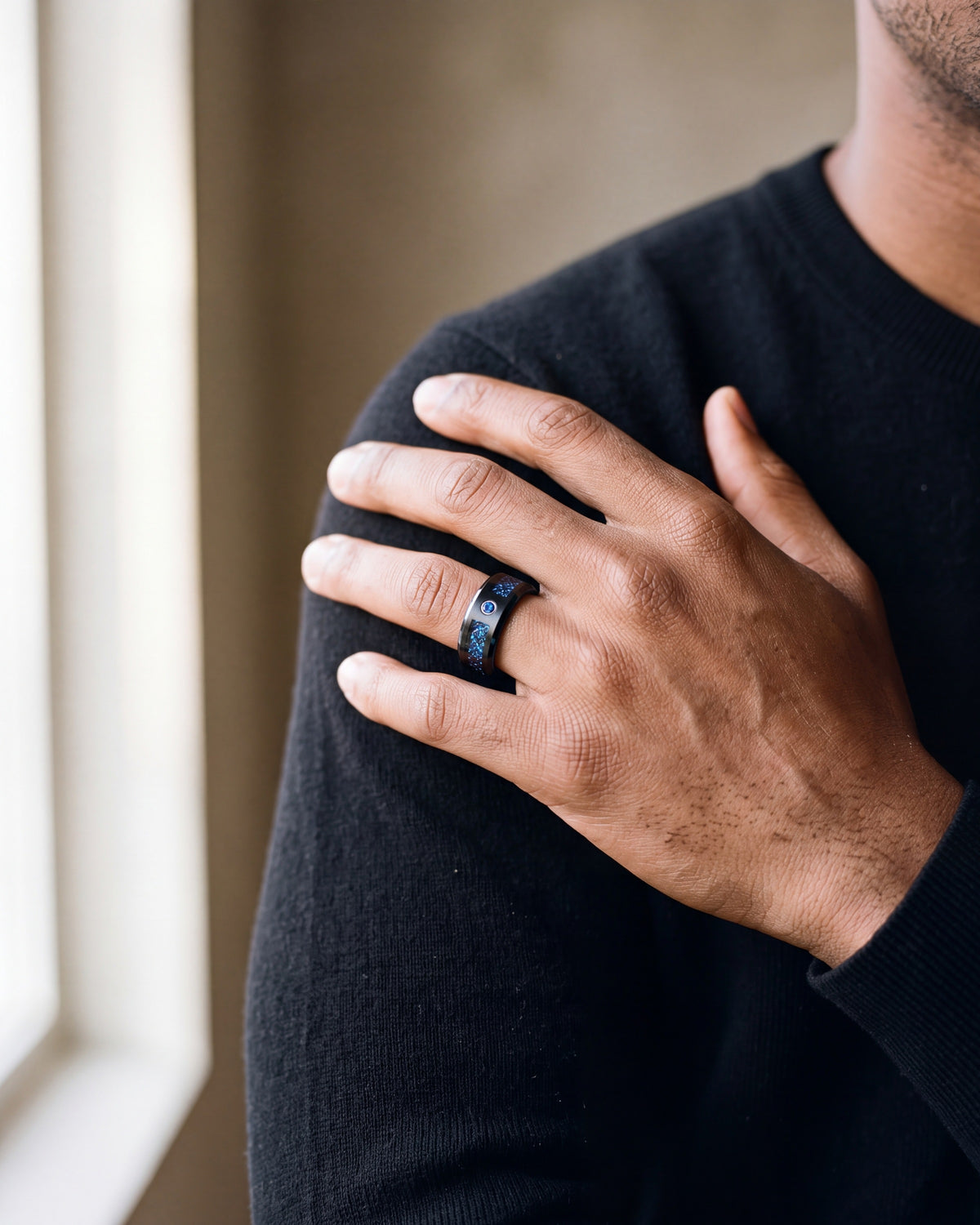 Close-up of the black and blue Atlas Celtic dragon inlay ring worn by a man, shown at true size