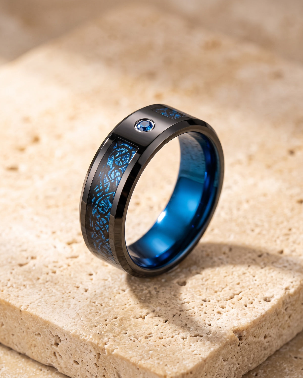 The whole black and blue Atlas Celtic dragon inlay ring laid on warm stone