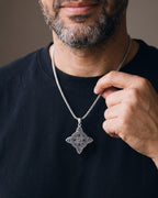 Hand lifting the Atlas Celtic Knot Necklace at the collarbone