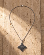 The silver Atlas Celtic Knot Necklace laid on warm travertine stone