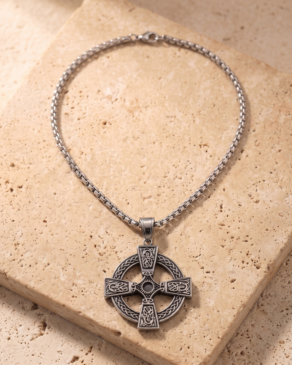 Atlas Celtic knotwork cross pendant and box chain laid whole on warm stone