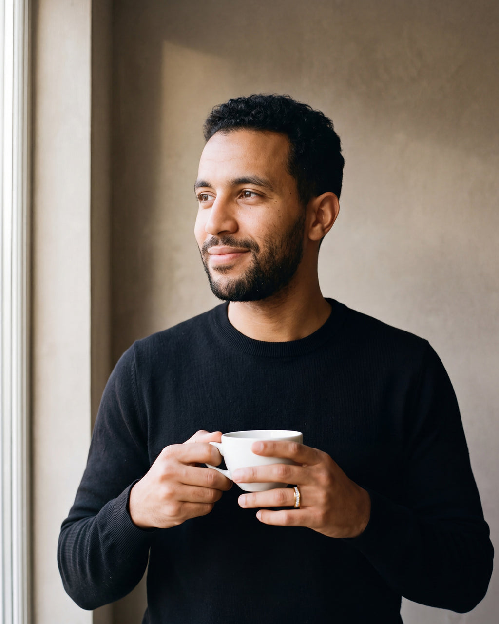 Man in a black knit holding a coffee cup, wearing the gold-tone Atlas cubic zirconia band ring