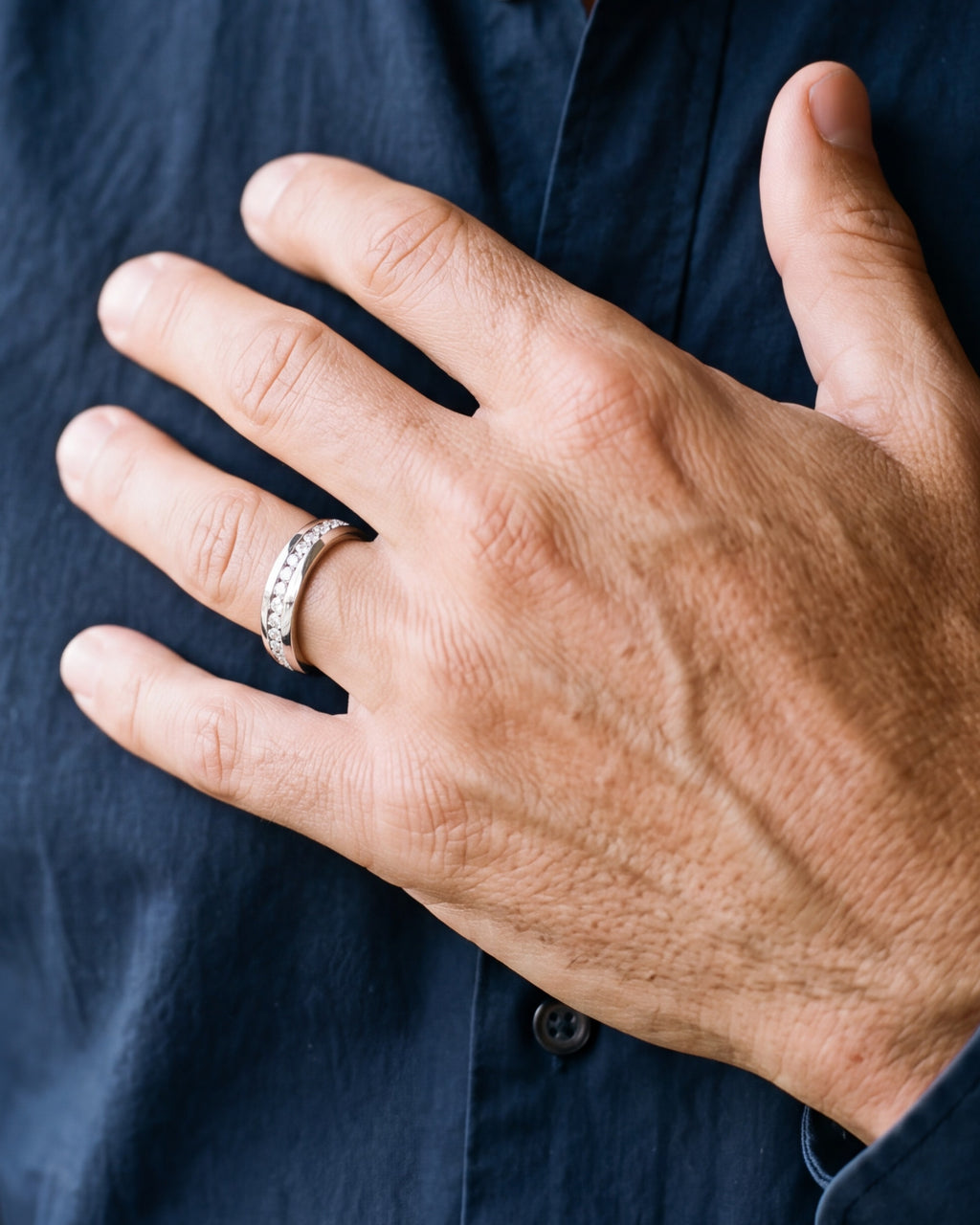 Close-up of a man's hand wearing the 6 mm silver Atlas channel-set band ring, shown at true size