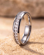 Silver Atlas cubic zirconia band ring standing on warm stone, showing the continuous channel of stones between polished rails