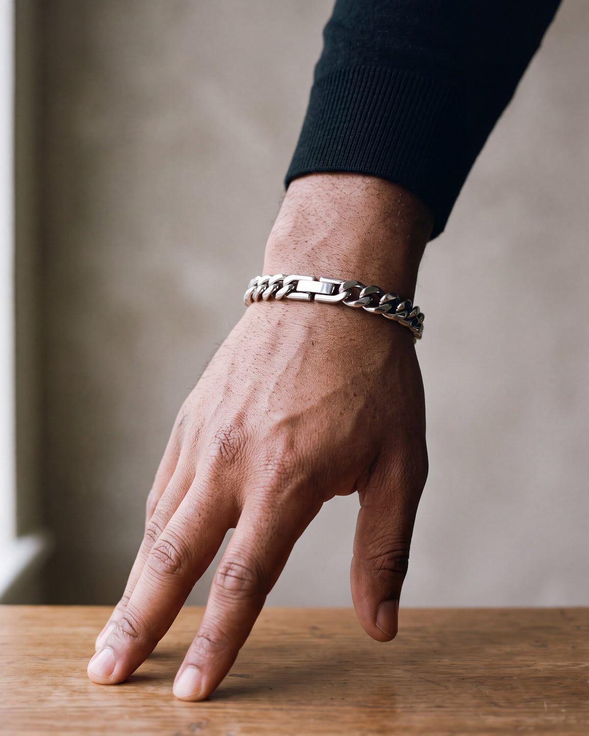 Close-up of the silver-tone Atlas classic Cuban link bracelet worn by a man, shown at true size