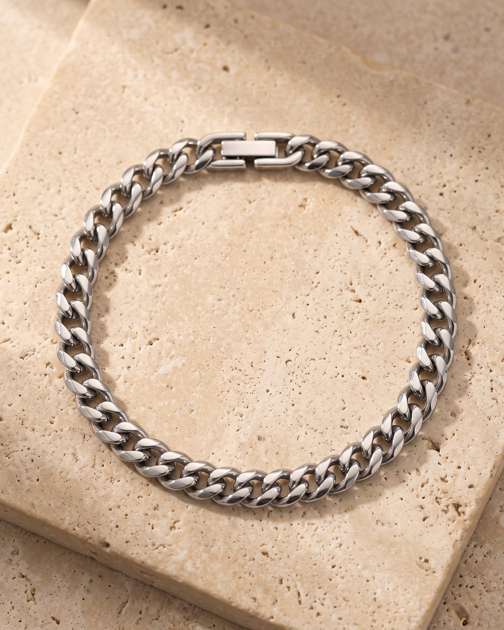 The whole silver-tone Atlas classic Cuban link bracelet laid on warm stone