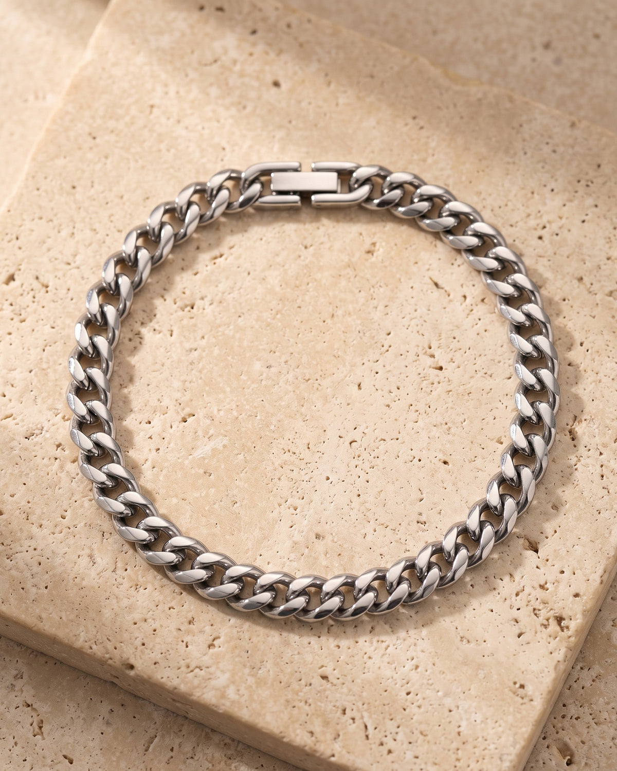 The whole silver-tone Atlas classic Cuban link bracelet laid on warm stone