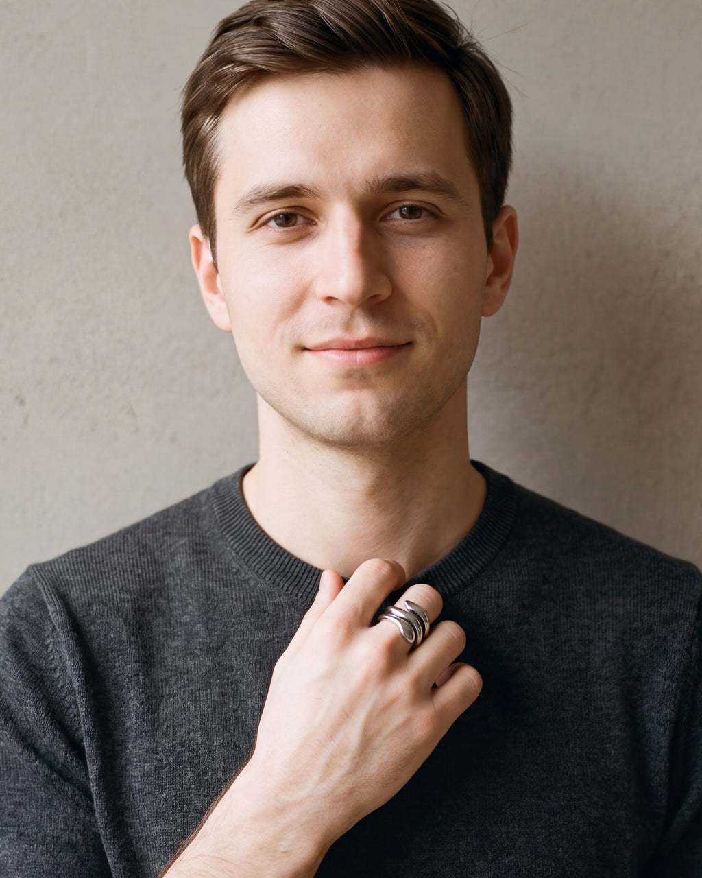 Man in a charcoal sweater with his hand at his collar, wearing the Atlas coiled snake ring