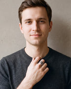 Man in a charcoal sweater with his hand at his collar, wearing the Atlas coiled snake ring