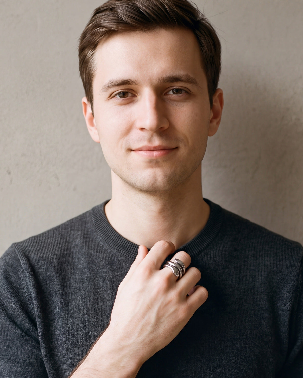 Man in a charcoal sweater with his hand at his collar, wearing the Atlas coiled snake ring